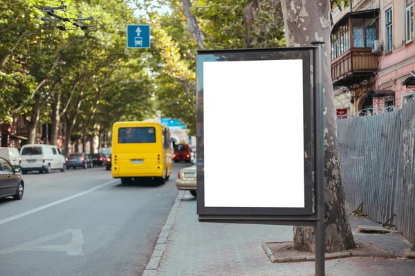 Boş, işlek bir caddede dikey sokak reklam panosuyla alay ediyor. Sarı otobüs şehirde özel bir hat üzerinde seyahat eder. — Stok fotoğraf