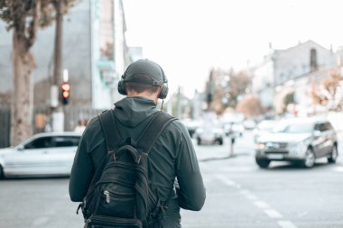 Sokakta kulaklıkla müzik dinleyen bir adamın arka görüntüsü..