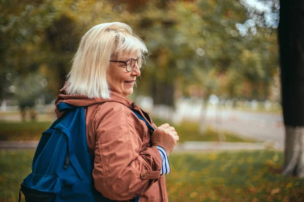 Mujer rubia caucásica con una mochila viaja por el parque — Foto de Stock