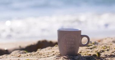 Beyaz kumsalda sıcak kahve ya da çay ve açık arkaplanda deniz..