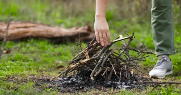 Νεαρή γυναίκα με σπίρτο ανάβει κλαδιά για τη φωτιά στο δάσος. — Αρχείο Βίντεο
