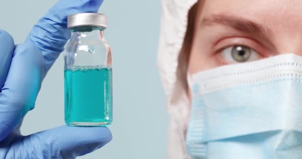 보호용 의료용 마스크를 착용하고 있는 의사나 간호사가 실험실이나 실험실에 유리 백신 병을 보관하고 있다. 건강 관리 개념 — 비디오
