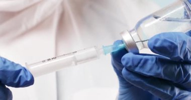 Coronavirus COVID-19 aşı şişesi. Kadın doktor ya da hemşire şırıngayı dolduruyor, aşıyı sıvı uyuşturucu ile tutuyor..