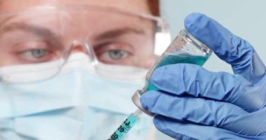 Doktor ya da hemşire koruyucu bir tıbbi maske ve mavi azot eldivenler içinde grip, kızamık, bebek ve yetişkin aşıları için koronavirüs aşısı.