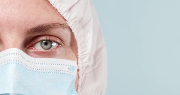 보호용 마스크를 착용하고 개인 보호 장비 복장을 한 여의사가 실험실에서 실험과 연구를 위해 투명 한 안경을 착용하고 있다. — 비디오