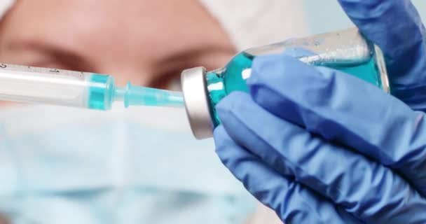 Arzt oder Krankenschwester in medizinischer Schutzmaske und Anzug hält eine Glasflasche mit COVID-19 Coronavirus-Impfstoff im Labor oder Labor — Stockvideo