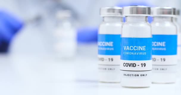 Lateks mavi eldivenli doktor ya da hemşire elinde şırınga ve Covid-19 Coronavirus aşı şişesi tutuyor. — Stok video