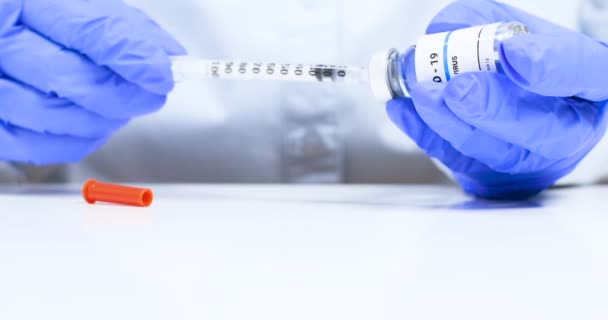 Detailní záběr ženských rukou lékaře v modrých lékařských rukavicích s průhlednou lahvičkou s tekutou koronavirovou vakcínou a injekční stříkačkou v laboratoři. Výzkum a vývoj nové léčby nemocí — Stock video