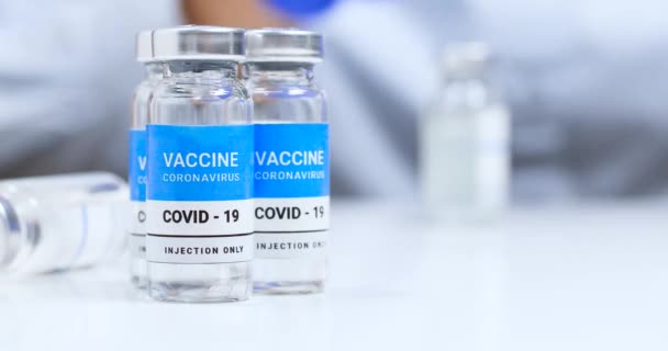 Il medico o l'infermiere in guanti di gomma blu lattice tiene una siringa e un flaconcino di vaccino Covid-19 coronavirus — Video Stock
