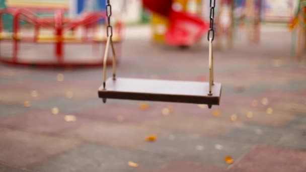 Pusty drewniany huśtawka z metalowymi łańcuchami na placu zabaw w parku miejskim. Bez dzieci i osób podczas pandemii koronawirusowej. — Wideo stockowe
