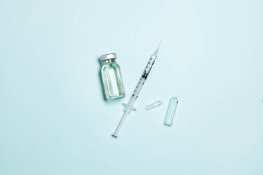 Mavi arka planda şırınga ve ampul bulunan ilaç şişesi. Aile bağışıklığı kavramı. Coronavirus, grip veya kızamık aşısı konsepti