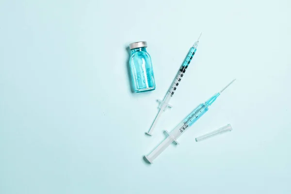 Vaccinflaska, glasampull och spruta med läkemedel på blå bakgrund. Minimal horisontell banderoll. Gdobal vaccination, vuxna och barn — Stockfoto