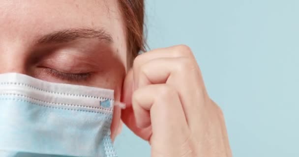 Een close-up van een arts of een medisch professional verwijdert een beschermend chirurgisch masker en ademt frisse lucht in na toediening van een groot aantal patiënten. — Stockvideo