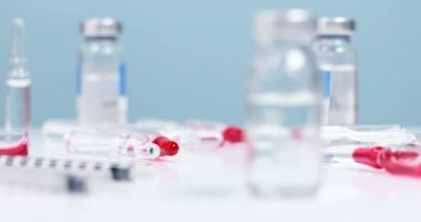 Grip, kızamık ya da kızamık aşısı sıvısı şişesinin laboratuvar masasının üzerinde yakın plan çekimleri, beyaz arka planda çeşitli ilaç ve şırıngalar bulunmaktadır. Sağlık kavramı