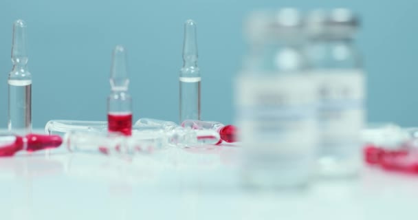 Coronovirus, nüfusun covid-19 aşısı. SARS-CoV-2 aşı şişesi camı ve şırıngayı kopyalama alanı olan beyaz bir laboratuvar masasında. Sığ alan derinliği — Stok video