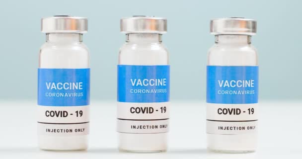 Koronowirus, szczepienie przeciw wiremii 19 populacji. Fiolki i strzykawka ze szczepionką SARS-CoV-2 na białym stole laboratoryjnym z przestrzenią do kopiowania. Koncepcja leczenia opieki zdrowotnej — Wideo stockowe