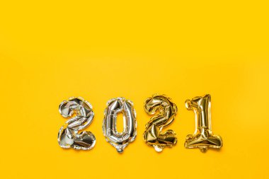 2021 altın folyo balon numaraları ve sarı arka planda fotokopi alanı. Yeni yıl ve Noel tatili konsepti.