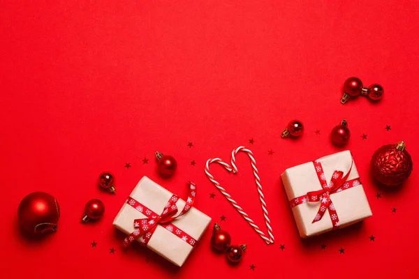 礼品盒用手工纸包着红丝带蝴蝶结 圣诞红糖手杖和红色背景的复制空间 现代创意最小的纯色假日作文 — 图库照片