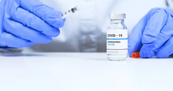 Corona virus Vaccine concept. Doctor hands in blue medical gloves with transparent liquid coronavirus vaccine bottle and syringe for injection in the laboratory. Research and development of new cure for diseases