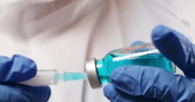 Doktor ya da bilim adamı ellerinde grip, kızamık, koronavirüs aşısı ve bebek ve yetişkin aşısı olan mavi nitril eldivenler tutuyorlar.