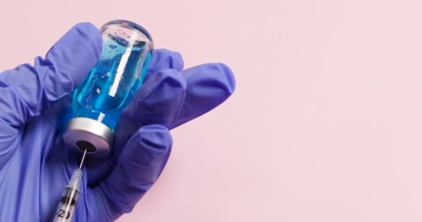 Läkarhänder i blå handskar som håller vaccinet nålspruta hypodermisk injektion dos för förebyggande immunbehandling sjukdom virus sjukdom — Stockvideo