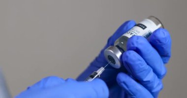 Koronavirüse karşı küresel aşı. Mavi cerrahi eldivenli doktor şırıngayı insanları, çocukları ve yetişkinleri aşılamak için ilaç aşısıyla dolduruyor.