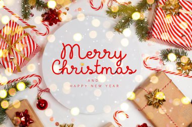 Hediye kutuları, altın kurdeleler, ışık, köknar dalı, şeker kamışı ve Mutlu Noeller metni içeren Noel tebrik kartı. Yeni yıl tatili geçmişi. Düz konum, üst görünüm, çerçeve