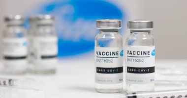 Odessa, Ukrayna - 9 Aralık 2020: Coronavirus yeni aşı sıvı şişeleri ve Pfizer logosu metin podyumunda yer aldı