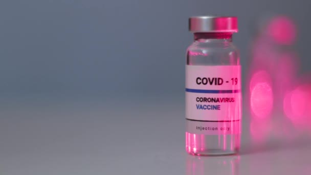 Nowa butelka z płynem zawierająca szczepionkę przeciw koronawirusowi Sars-cov-2 na białym stole. Badania i rozwój nowego lekarstwa na choroby — Wideo stockowe