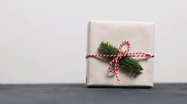 Kadın eli, her zaman yeşil ladin dallarıyla süslenmiş ve arka planda kırmızı-beyaz şeritli bir musibetle süslenmiş bir Noel hediyesi kutusu alır. Noel ve Yeni Yıl afişi.