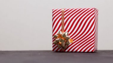 Kadın eli, çizgili kırmızı-beyaz kağıda sarılı güzel bir Noel hediyesi kutusunu karanlık bir masaya götürür. Noel ve Yeni Yıl kavramı