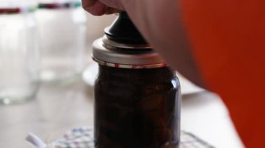 Kadın eli salamura ve konserve Armillaria mellea mantarlarını cam bir kavanoza doldurur..
