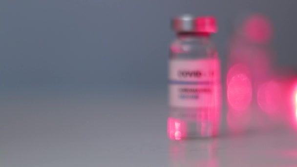 Nowa butelka z płynem zawierająca szczepionkę koronawirusową na białym stoliku z miejscem na tekst. Badania i rozwój nowego lekarstwa na choroby — Wideo stockowe