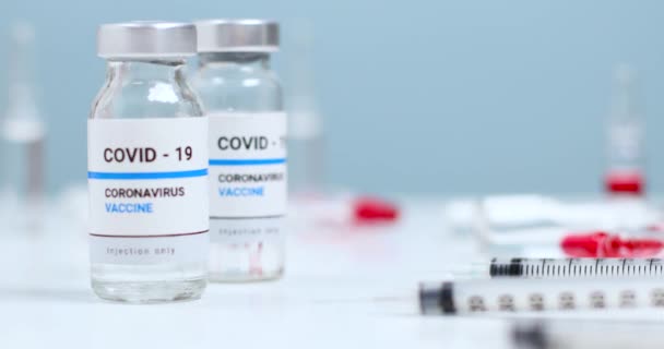 Coronavirus. Covid-19 viales de frasco de vidrio de vacuna de medicamentos con líquido transparente en el laboratorio. Jeringas con aguja para inyección y vacunación en masa. — Vídeos de Stock