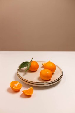 Taze mandalina ya da bej bir tabakta mandalinalı meyveler, beyaz arka planda altın kenarlı. Renkli meyve arka planı. Dekoratif noel kompozisyonu