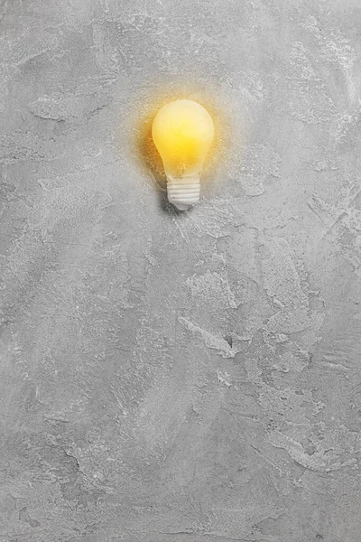Bright idea illuminated light bulb on grey background. Creative inspiration, planning ideas concept. Flat lay, top view with copy space