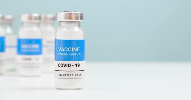 Coronovirus, nüfusun covid-19 aşısı. SARS-CoV-2 aşı şişesi camı ve şırıngayı kopyalama alanı olan beyaz bir laboratuvar masasında. Sağlık tedavisi konsepti. 4k — Stok video