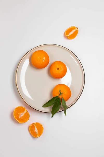 Frutas frescas de mandarina o clementina en un plato beige con un borde de oro sobre la mesa. Fondo de fruta de colores. Piso tendido, vista superior, espacio para copiar. Composición decorativa navideña — Foto de Stock