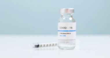 Mavi masadaki mavi masada Coronavirus SARS-CoV-2 virüsüne karşı şırıngalı COVID-19 temiz sıvı aşı şişesi..