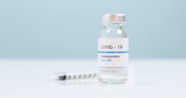 Flacon de vaccin liquide propre COVID-19 avec seringue contre le virus du coronavirus SRAS-CoV-2 sur table bleue en laboratoire. — Video