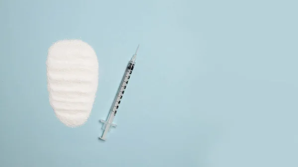 Seringa com uma agulha e medicina em um fundo azul com espaço de cópia. Um monte de droga branca, vista de cima. Dependência química e dependência química, conceito de drogas ilegais — Fotografia de Stock