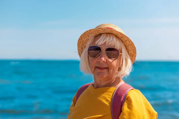 Kvinna resenär i sommar hatt och solglasögon står på stranden och har en vacker utsikt — Stockfoto
