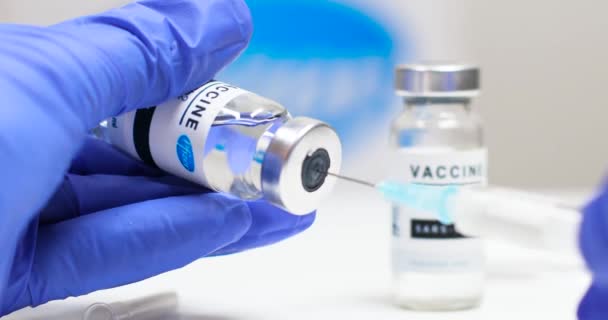 Globale vaccinatie tegen het coronavirus. Hand van een arts gebruik een injectiespuit om een injectie te nemen uit de injectieflacon met vaccin tegen covid 19 Sars-cov-2. — Stockvideo