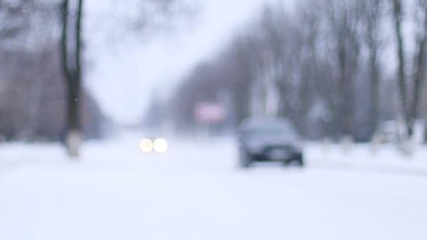 Обезжиренный боке. Автомобили, движущиеся в движении по заснеженной дороге во время зимней метели — стоковое видео