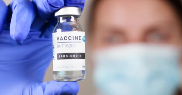 Одесса, Украина - 9 декабря 2020 года: Врач или медсестра в защитной медицинской маске и латексных перчатках с новой вакциной против опасного коронавируса. — стоковое видео