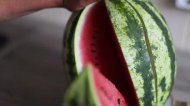 Kadın eli bir parça karpuz alır. Tahtada olgun meyveli yaz kavramı.