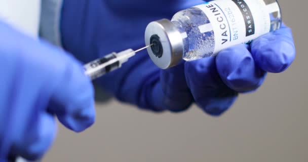 Врач или медсестра в защитных медицинских резиновых перчатках проводит новую вакцину и шприц против коронавируса Сарс-Ков-2, коронавируса или ковида-19 — стоковое видео