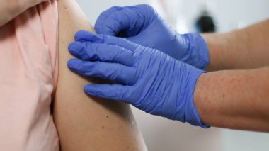 Tıbbi maskeli hastaya iğne yapmadan önce şırınga tutan ve pamuk kullanan bir doktor. Aşı ve grip veya virüs salgınına karşı önleme.