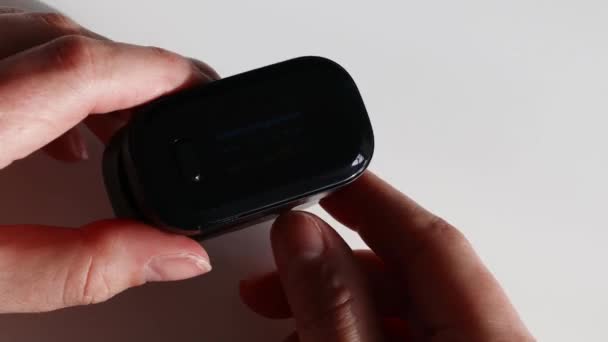 Woman hands holding digital pulse oximeter and looking at device — Stock Video