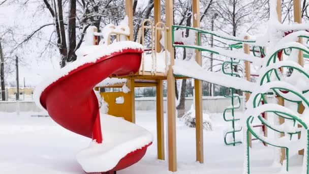 Пустые детские площадки во время снегопада. Заснеженные деревья. — стоковое видео